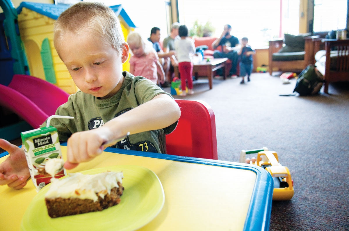 Above, a young patron at Sovereign Grounds in Minneapolis digs into a wedge of carrot cake. At top, customers at Village Bean in Bothell, Washington, enjoy coffee and light reading in the café's play space. (Photo: courtesy Sovereign Grounds.