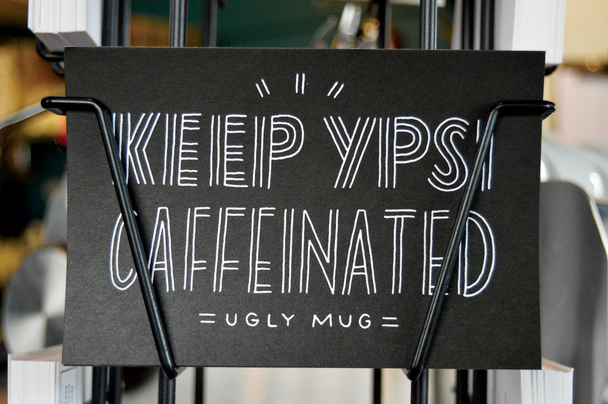 Keep Ypsi Caffeinated postcard by a local printmaker are on sale at the Ugly Mug. (Photos by Jessica Copi.)