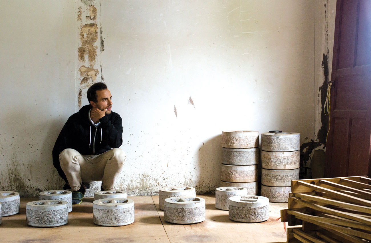 Lozito crouches among the weights that are used to press pu-erh.
