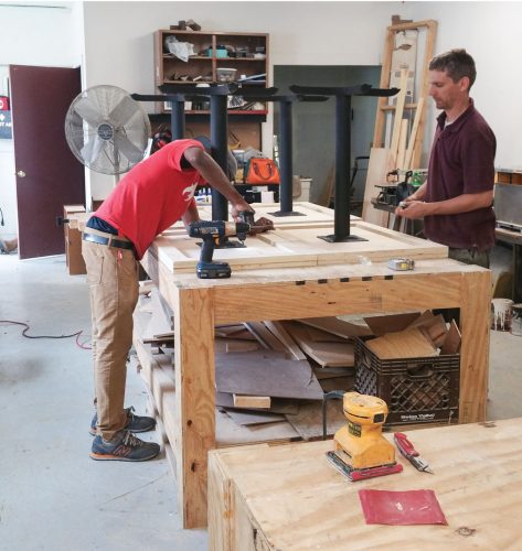 Workers construct café tables from reclaimed materials at L!VE Café in Chicago, Illinois.